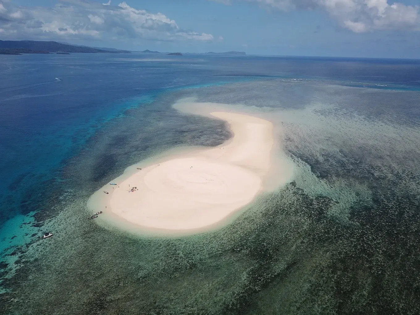 L’îlot de sable blanc vu du ciel, cerné par le récif